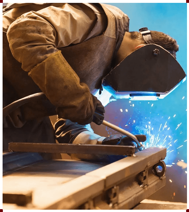 A man welding metal with blue light coming from the bottom.